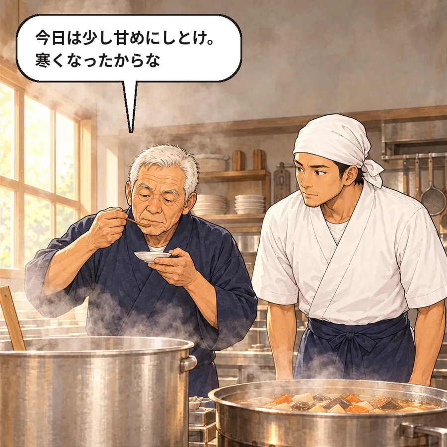 朝の厨房。大きな鍋から湯気が立ち、先代の父が小皿で煮物の味見をしている。片山さんが横で真剣に見ている